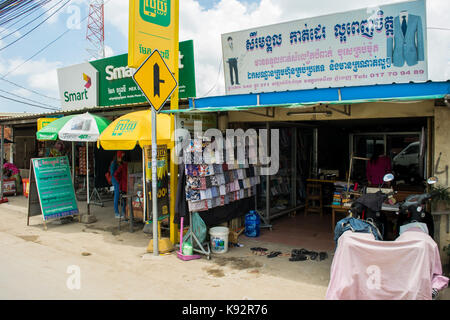 A shop selling textiles and cloth, with samples of different colours and patterns on display outside. In the streets of Phnom Penh, Cambodia, SE Asia Stock Photo