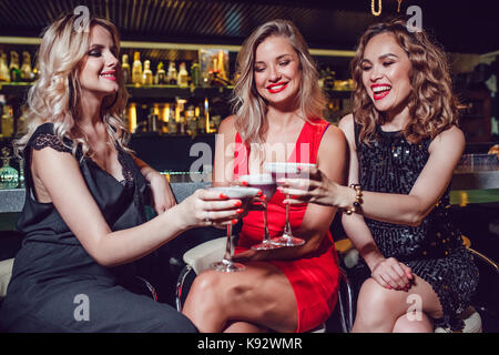 Beautiful women are sitting on the bar and drinking cocktails. Stock Photo
