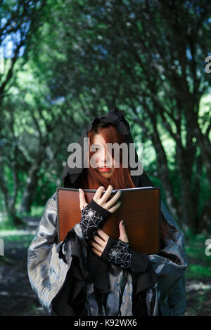 Photo of witch in cloak with book Stock Photo