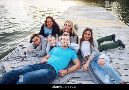 Group of beautiful young people on the pier, friends satisfaction creates emotional life Stock Photo