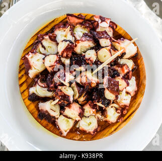 Delicious Spanish octopus on wooden plate pulpo a la gallega. Typical Galician spanish tapas - Pulpo a Feira. Coocked octopus with olive oil served in Stock Photo