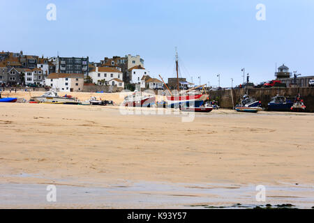 Fishing and pleasure boats beached on the strand at St Ives, Cornwall, at low tide Stock Photo