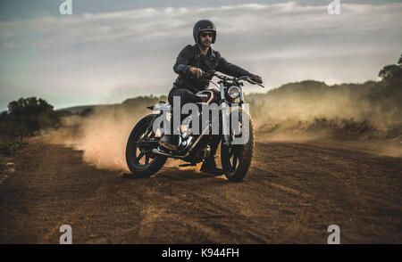 Three men wearing open face crash helmets and goggles riding cafe racer  motorcycles along rural road Stock Photo - Alamy