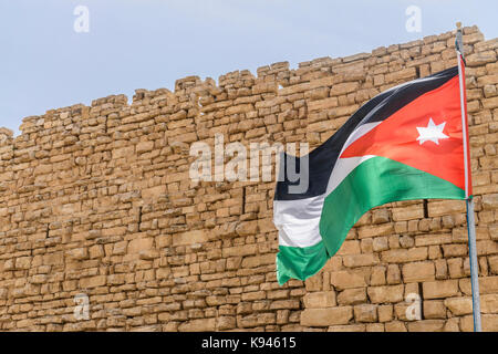 Jordanian flag flying outside stone wall of Kerak Castle, a Crusader castle in al-Karak. Stock Photo