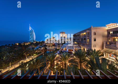 Cityscape of the Dubai, United Arab Emirates at dusk, with illuminated buildings and the Burj Al Arab in the distance. Stock Photo
