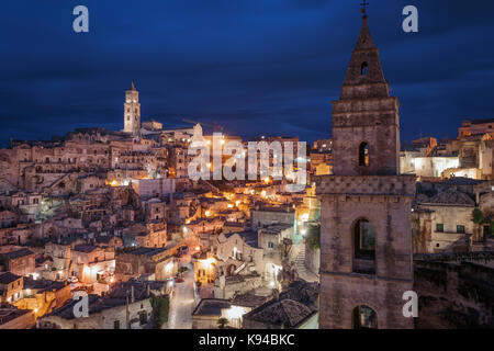 The bell tower or the church of San Pietro Barisano and the Civita with the Cathedral lit up at night, Sassi di Matera, Basilicata, Italy. Stock Photo