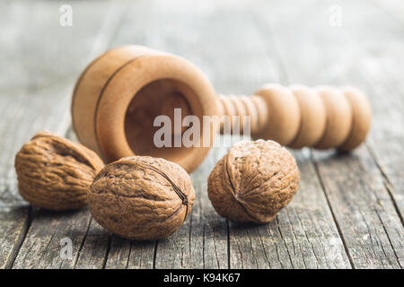Dried walnuts and nutcracker on wooden table. Stock Photo