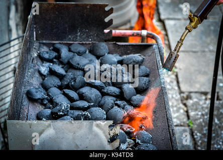 Firing up charcoal briquettes for the BBQ grill. Starting a grill with propane gas torch. Stock Photo