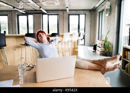 Beautiful businesswoman with laptop in the office with her feet up on desk. Stock Photo