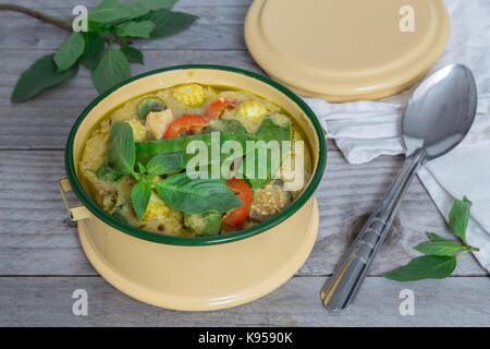 Green Thai curry in a bowl on wooden table. Stock Photo