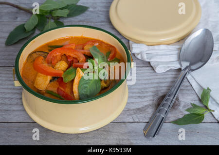 Red Thai curry in a bowl on wooden table. Stock Photo
