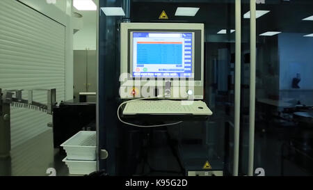 Computer in laboratory or manufactory. Biochemical analyzer and computer in laboratory of wine industry. Analyzing data scientist in the laboratory with a screen project development researcher touching the screen of report research data. Caucasian scientist doing experiment while writing the observation result on the clipboard. The operator of the measuring station. Science and medicine Stock Photo