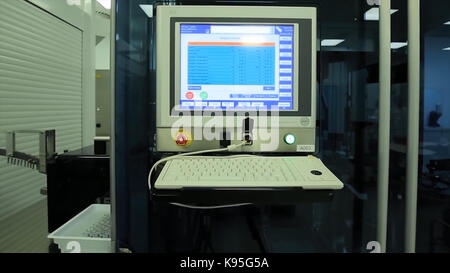 Computer in laboratory or manufactory. Biochemical analyzer and computer in laboratory of wine industry. Analyzing data scientist in the laboratory with a screen project development researcher touching the screen of report research data. Caucasian scientist doing experiment while writing the observation result on the clipboard. The operator of the measuring station. Science and medicine Stock Photo