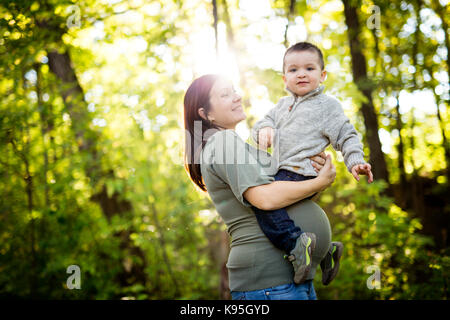 cute child with mother pregnant woman in forest Stock Photo