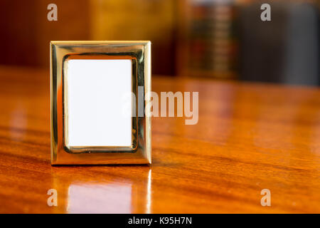 A square golden picture frame on wooden table Stock Photo