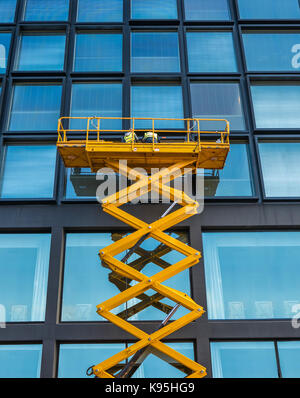 Workers On A Scissor Lift Cleaning Windows On A Financial Building Downtown Stock Photo