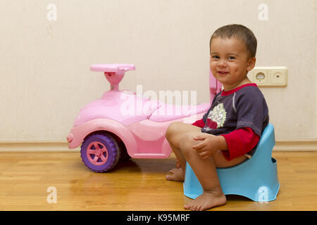 smiling child sitting on chamber pot indoors Stock Photo