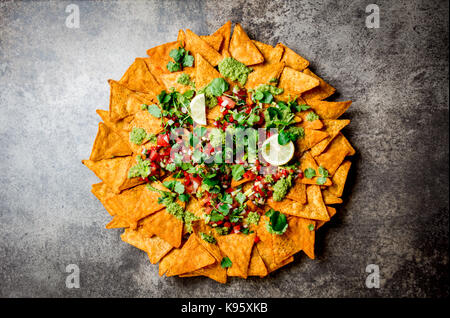 Nachos. Mexican food concept. Yellow corn totopos chips with different sauces salsas - pico del gallo, guacamole, salsa verde, chili pebre and fresh a Stock Photo