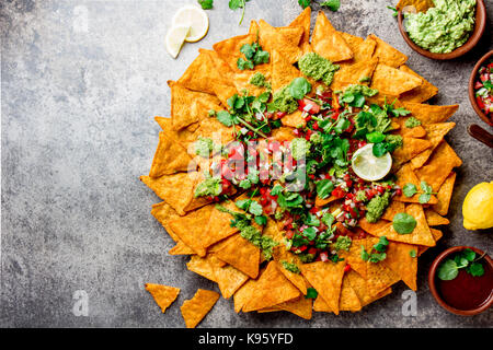 Nachos. Totopos with sauces. Mexican food concept. Yellow corn totopos chips with different sauces salsas - pico del gallo, guacamole, salsa verde, ch Stock Photo