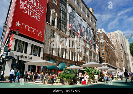 People walking & relaxing at the pedestrian mall next to the side entrance of Macy's Department Store at 34th Street & Broadway in midtown Manhattan. Stock Photo