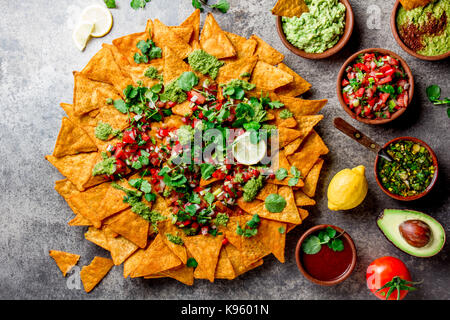 Nachos. Mexican food concept. Yellow corn totopos chips with different sauces salsas - pico del gallo, guacamole, salsa verde, chili pebre and fresh a Stock Photo