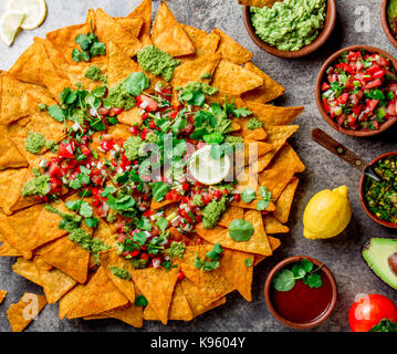 Nachos. Mexican food concept. Yellow corn totopos chips with different sauces salsas - pico del gallo, guacamole, salsa verde, chili pebre and fresh a Stock Photo
