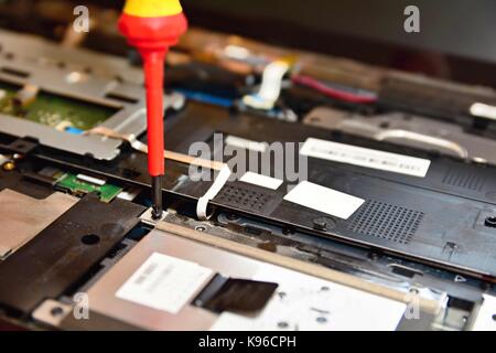 Closeup shot of screwdriver during repairing of the old notebook computer. Stock Photo