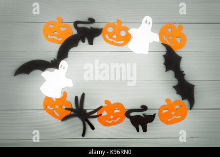 Halloween holiday background made of frame with pumpkins, bats, cats, spiders and ghosts cut paper on gray board. Copy space. Light up Stock Photo