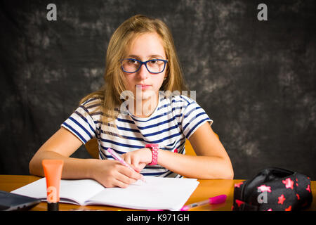 Bored teenage girl doing homework assignment at home Stock Photo