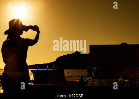 Silhouette of girl taking pictures with mobile phone. With sunset. Stock Photo