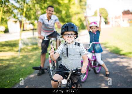 Dad With Daughter Son Riding Bikes In Park Stock Photo