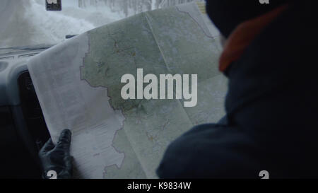 Losted in the forest driver sitting in car while holding map. Man looks at a map while sitting in car Stock Photo