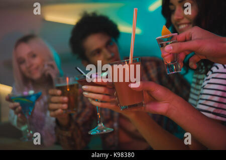 multiethnic friends clinking cocktails in bar Stock Photo