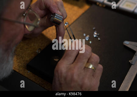 Close-up of goldsmith using magnifying glass in workshop Stock Photo