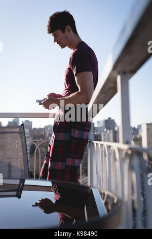 Handsome man using mobile phone on terrace Stock Photo