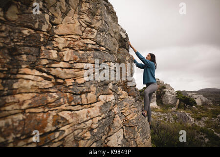 Determined woman climbing cliff on a sunny day Stock Photo