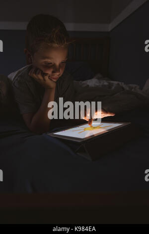 Cute boy using digital tablet in bedroom Stock Photo