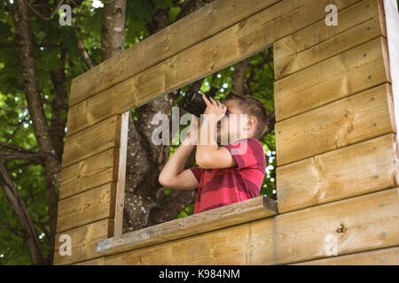 Boy looking through binoculars in playground Stock Photo