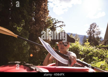 Boy in pirate costume sitting in boat on a sunny day Stock Photo