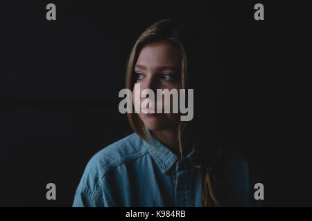 Thoughtful young woman looking away while standing in darkroom Stock Photo