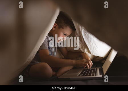 Cute boy using laptop in bedroom Stock Photo