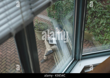 Man talking on mobile phone while working on laptop in the garden Stock Photo