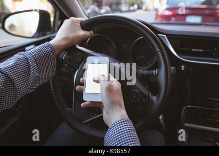 Close-up of man using mobile phone while driving car Stock Photo