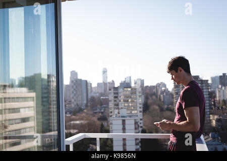 Handsome man using mobile phone on terrace Stock Photo