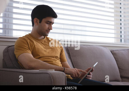 Man using digital tablet on sofa in living room at home Stock Photo