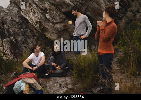 Friends interacting with each other while having coffee during mountaineering Stock Photo