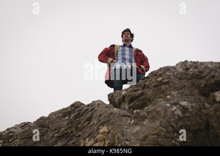 Hiker standing on top of the cliff on a sunny day Stock Photo