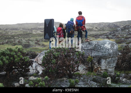 Rear view of friends standing on top of the cliff Stock Photo