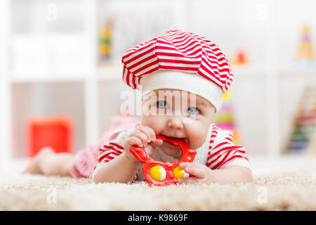 Child girl weared costue biting a toy lying on a carpet at home Stock Photo