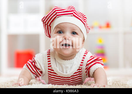 Six months old baby girl lying on carpet on floor in nursery Stock Photo
